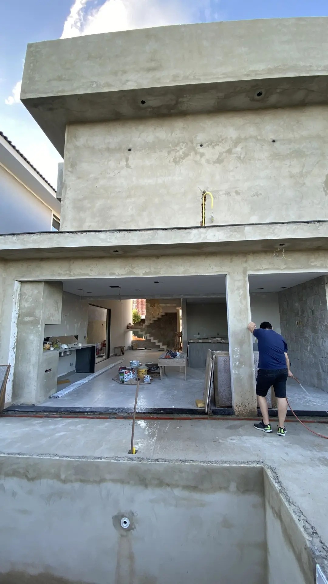 Exterior de uma moradia em construção, com a fachada por acabar e um trabalhador na entrada