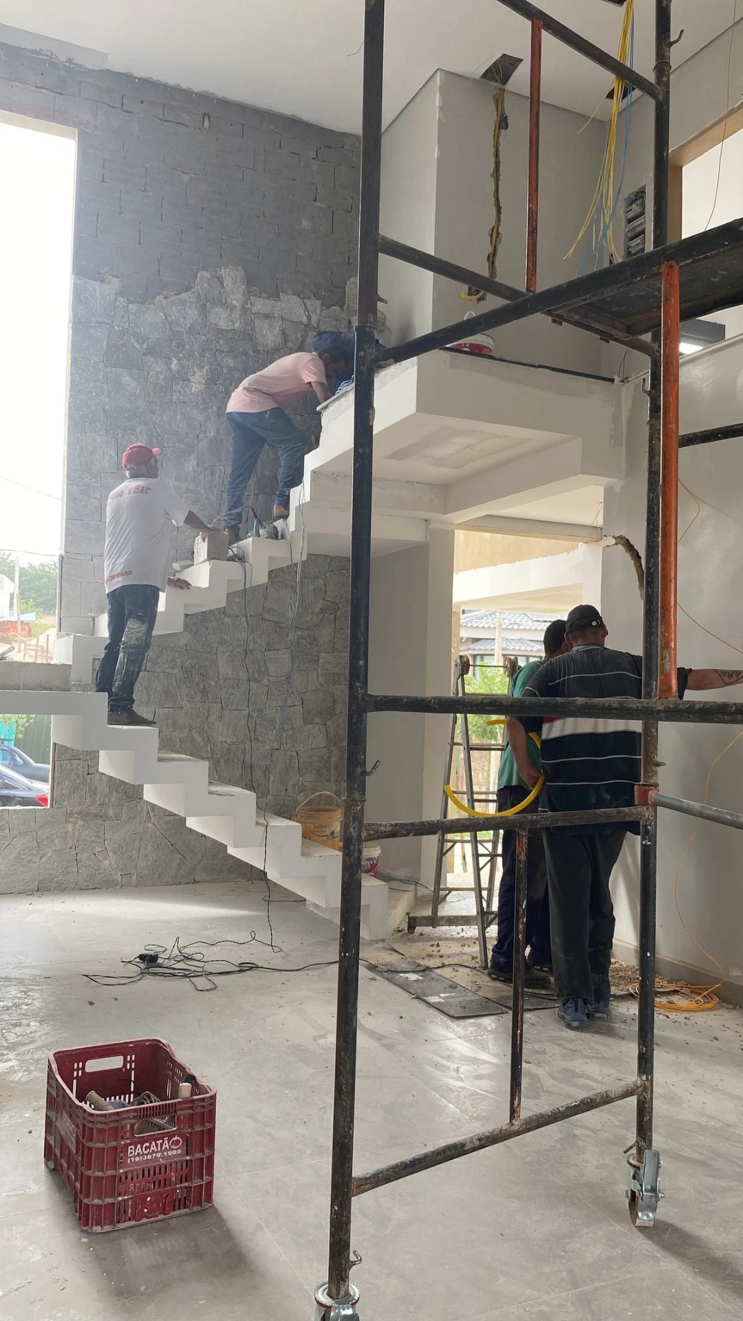 Escada interior em construção, com andaimes e trabalhadores durante a execução da obra